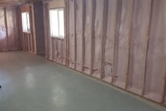 Alt Text: Open stud walls in a residential basement filled with pink spray foam insulation installed around windows and electrical wiring by Classic Spray Foam.