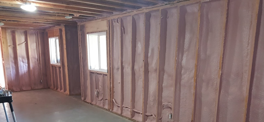 Closed-cell spray foam insulation installed between wall studs in an older Edmonton home to reduce drafts and improve energy efficiency.